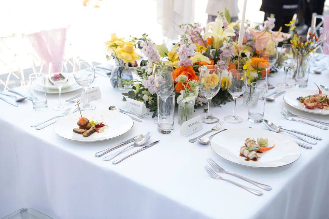 Minimalist reception space with simple long tables, clean place settings, and focus on lighting