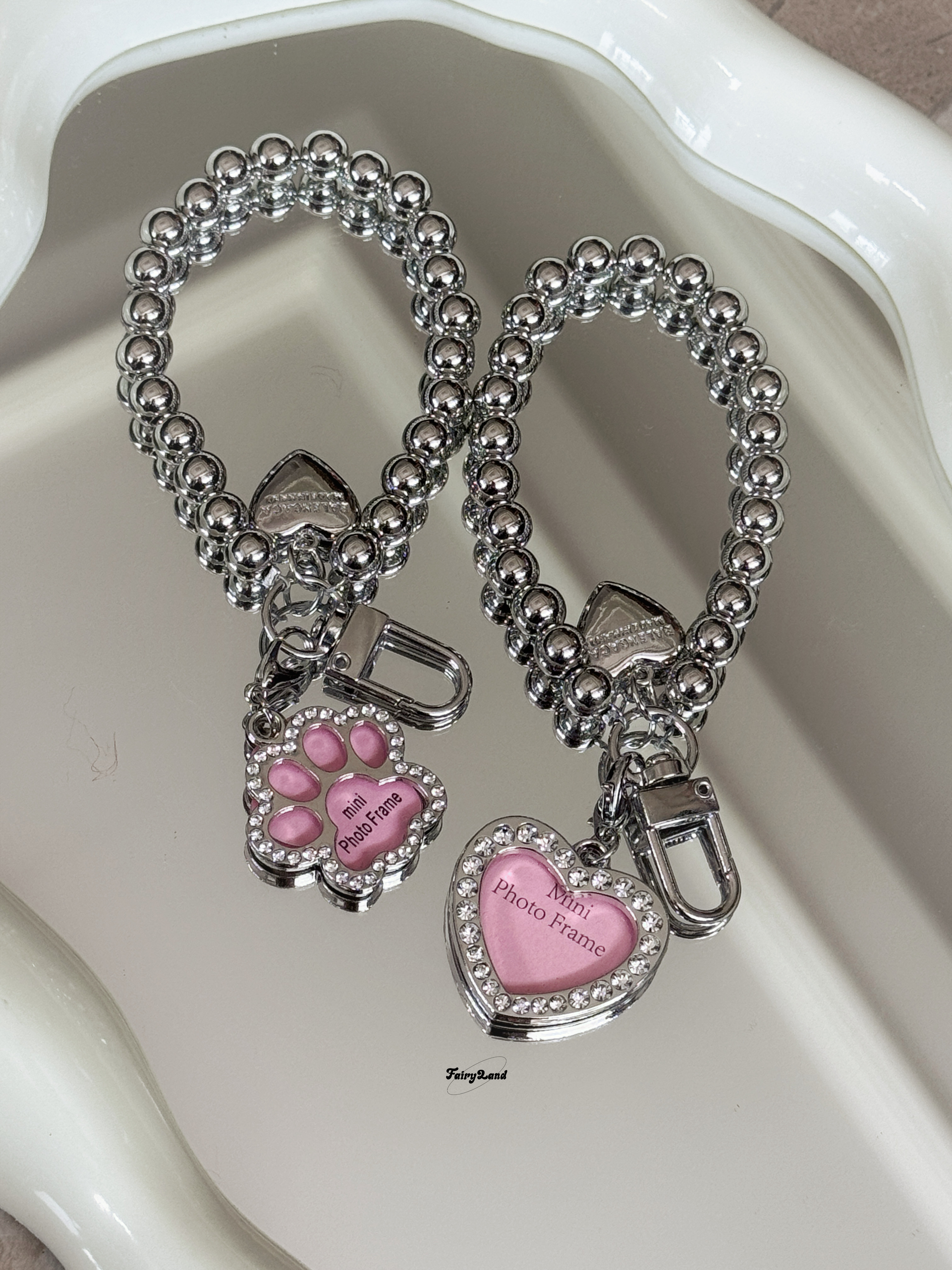 Instagram-style rhinestone-embellished heart-shaped dog bone keychain/phone charm with metallic pink frame and phone chain.