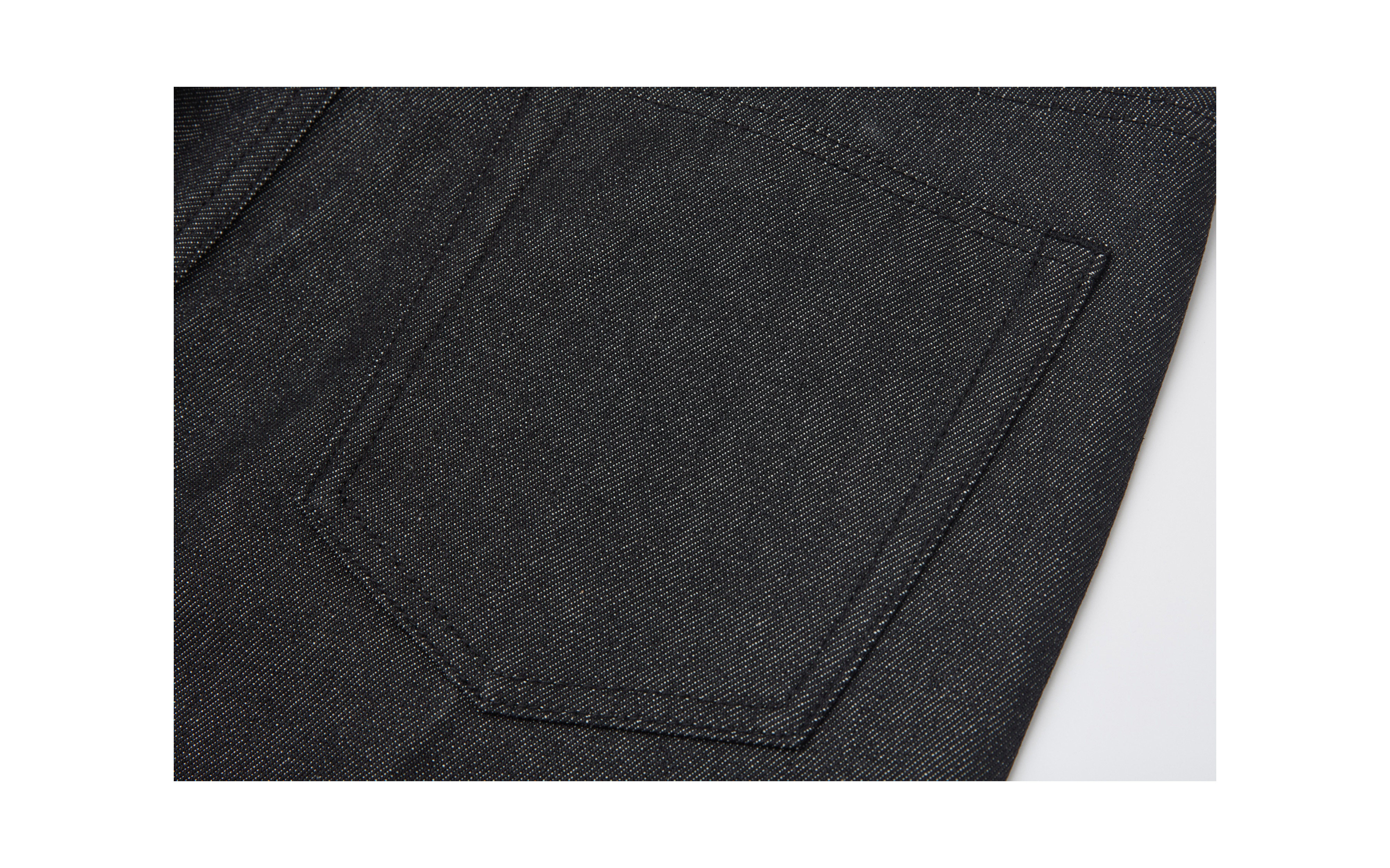 Close-up of EastLyst’s Colorfast Black Flared Jeans: black cotton-poly denim with visible seams and textured stitched pocket, photographed from above.