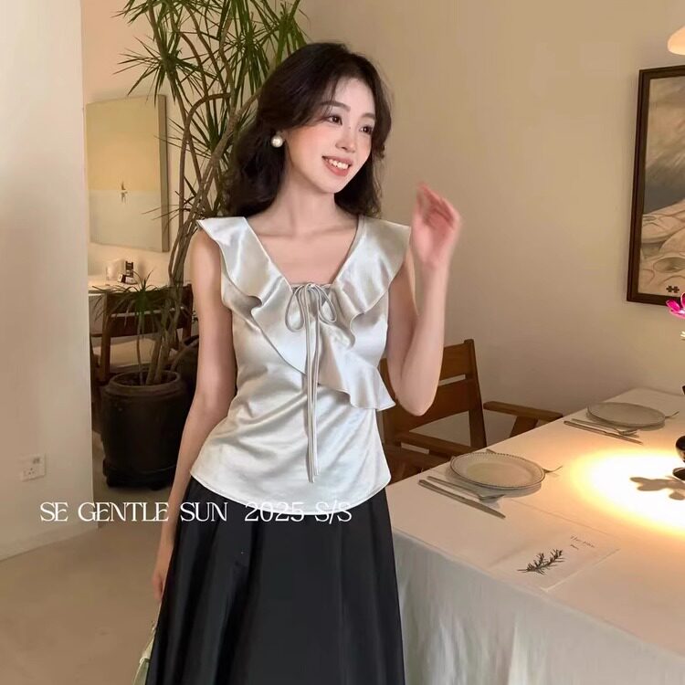 Woman wearing a silver ruffled sleeveless satin top with a black skirt
