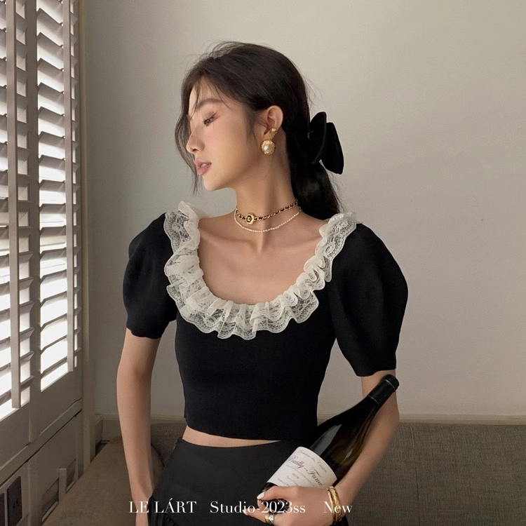 Black puff-sleeve top with white lace ruffle trim worn by a model