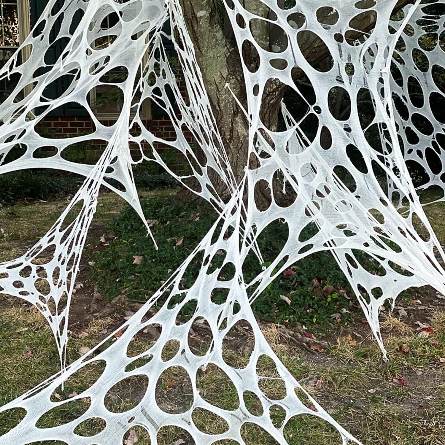 Halloween spider web decorations, realistic giant fake plush spiders, outdoor scene decorations for a scary atmosphere.