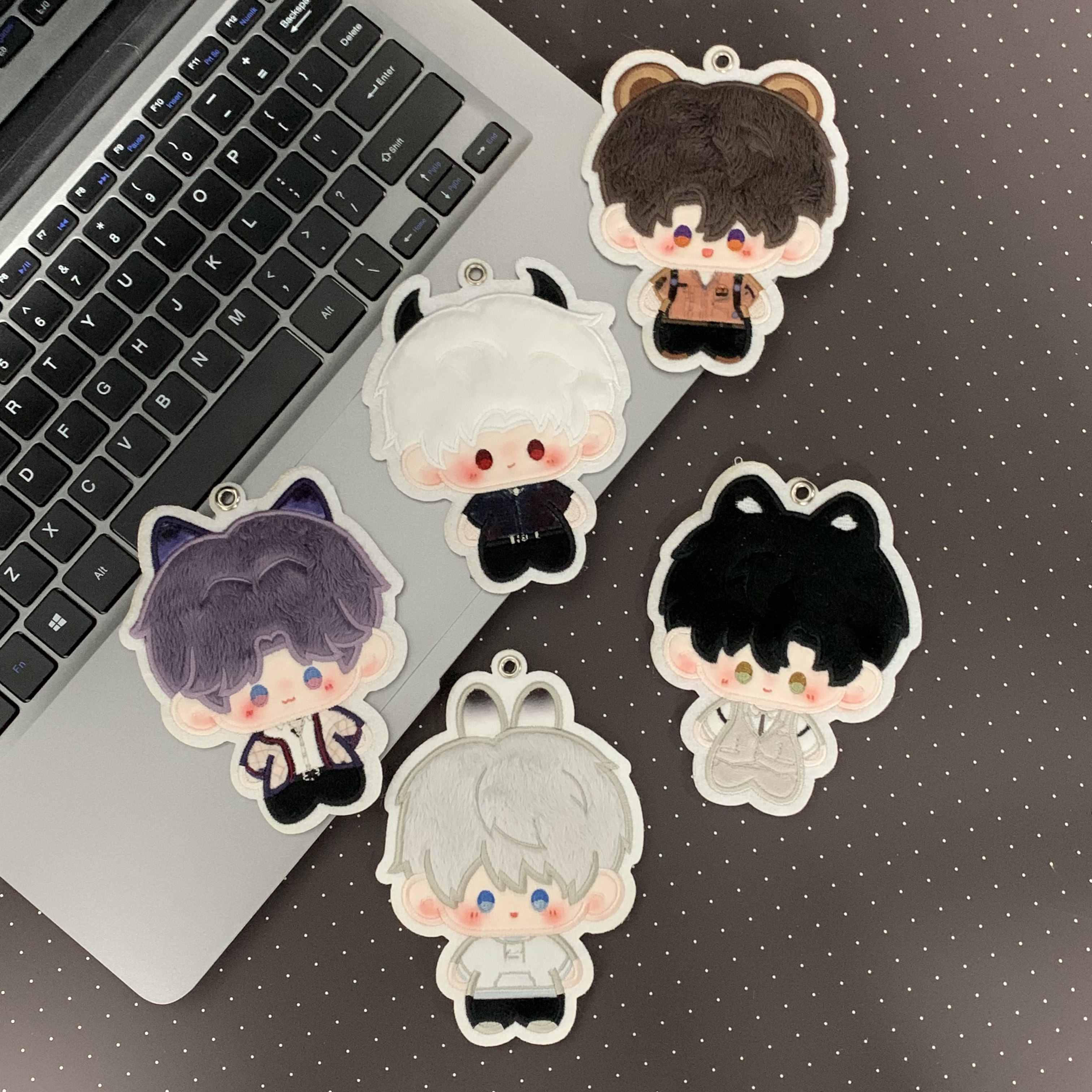 Five fan-made Love and Deepspace plush charms beside a laptop