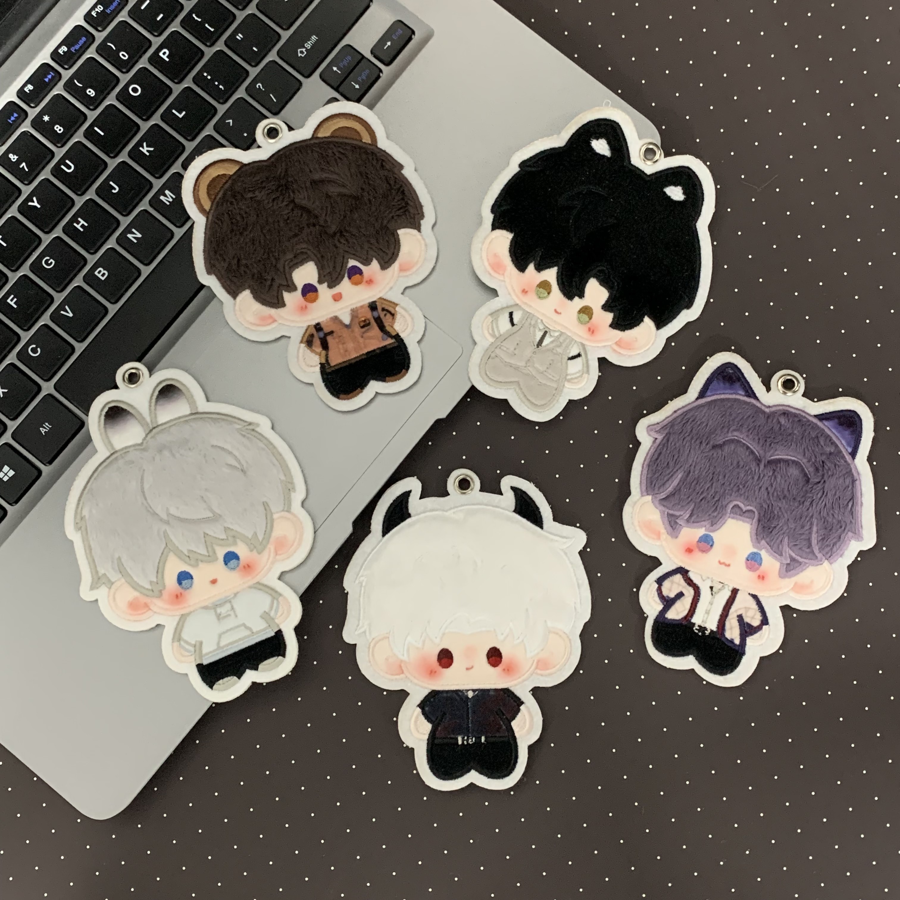 Love and Deepspace plush charms arranged around a laptop