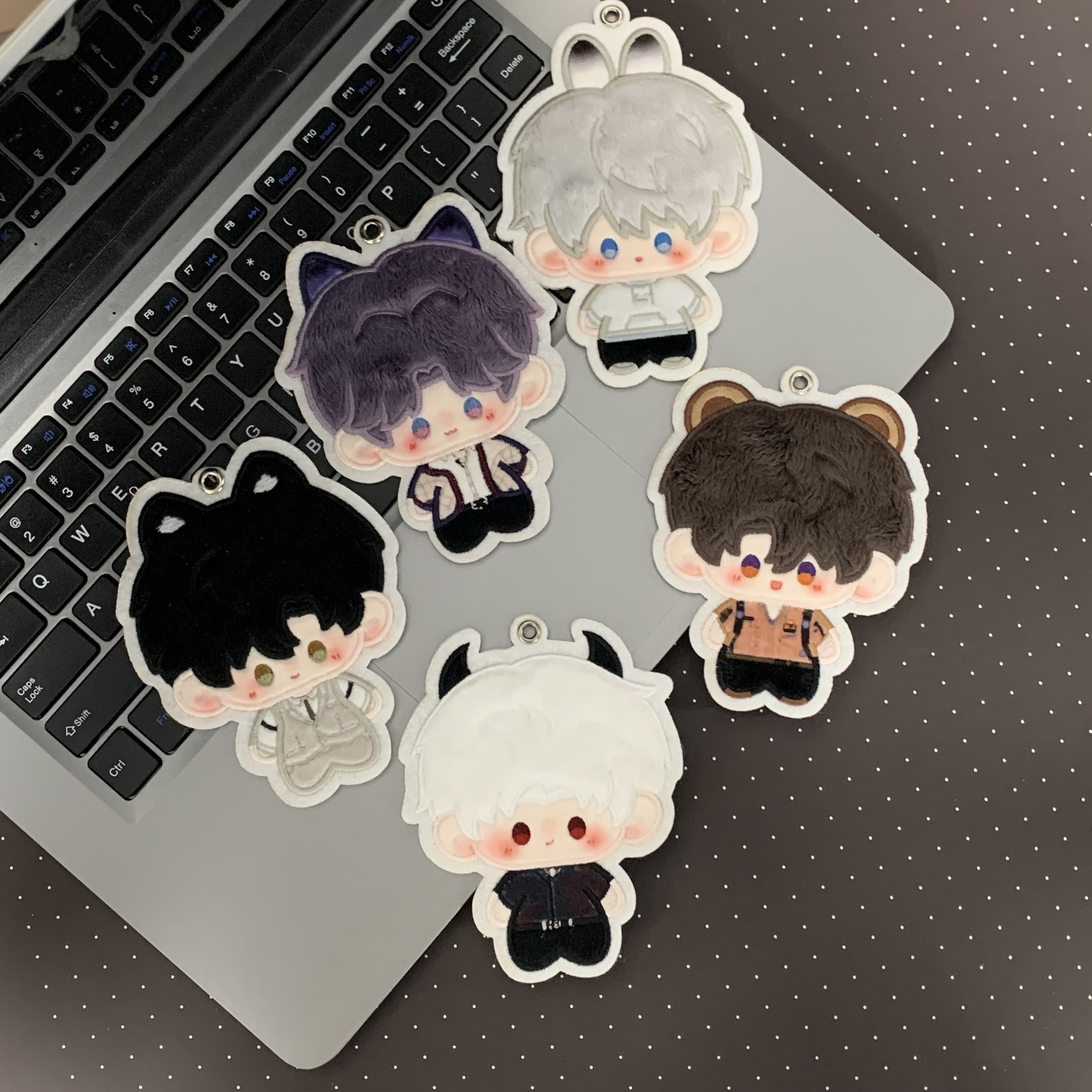 Five Love and Deepspace animal-ear plush charms beside a laptop