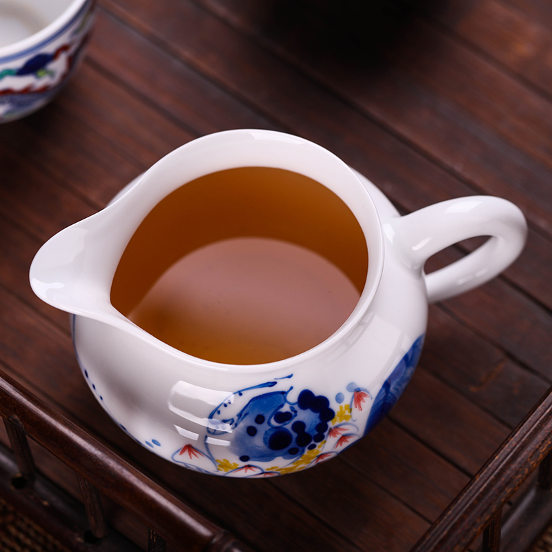 Jingdezhen hand - made ceramic fair cup of tea by hand and points tea exchanger with the ceramics cup against the hot cup of tea sea