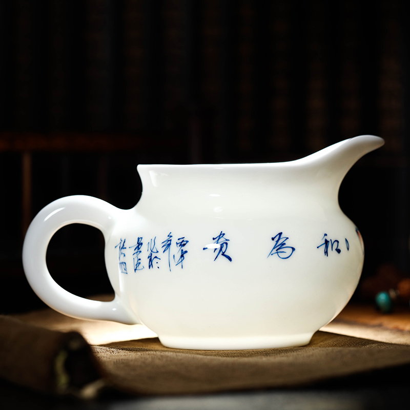 Jingdezhen hand - made ceramic fair cup of tea by hand and points tea exchanger with the ceramics cup against the hot cup of tea sea