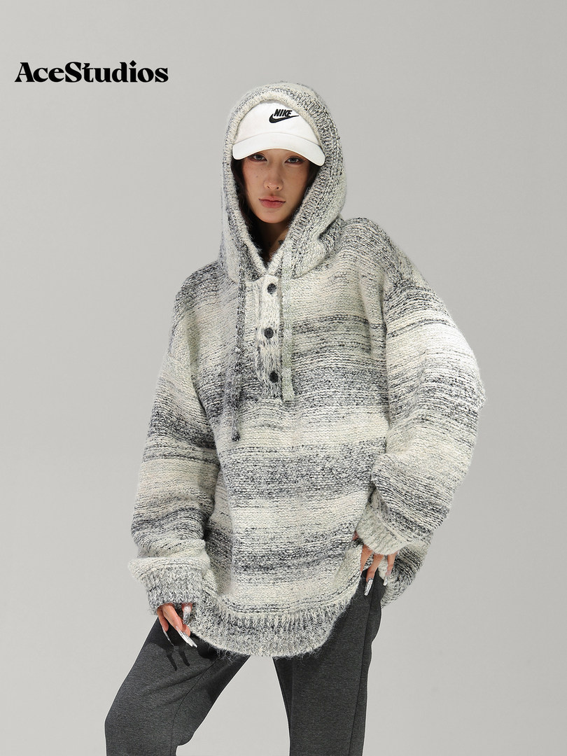 Model wearing an oversized gray knit hooded pullover with a white cap.