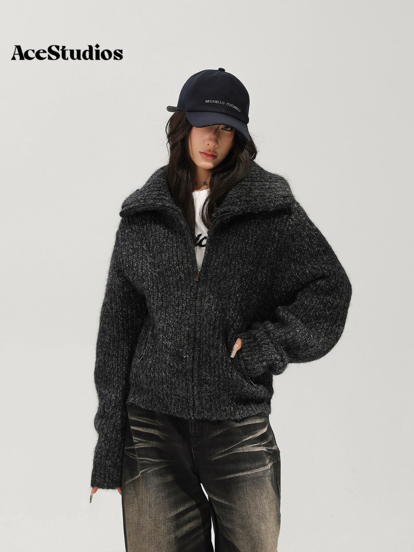 Model wearing a dark textured zip-up jacket, black cap, and distressed jeans.
