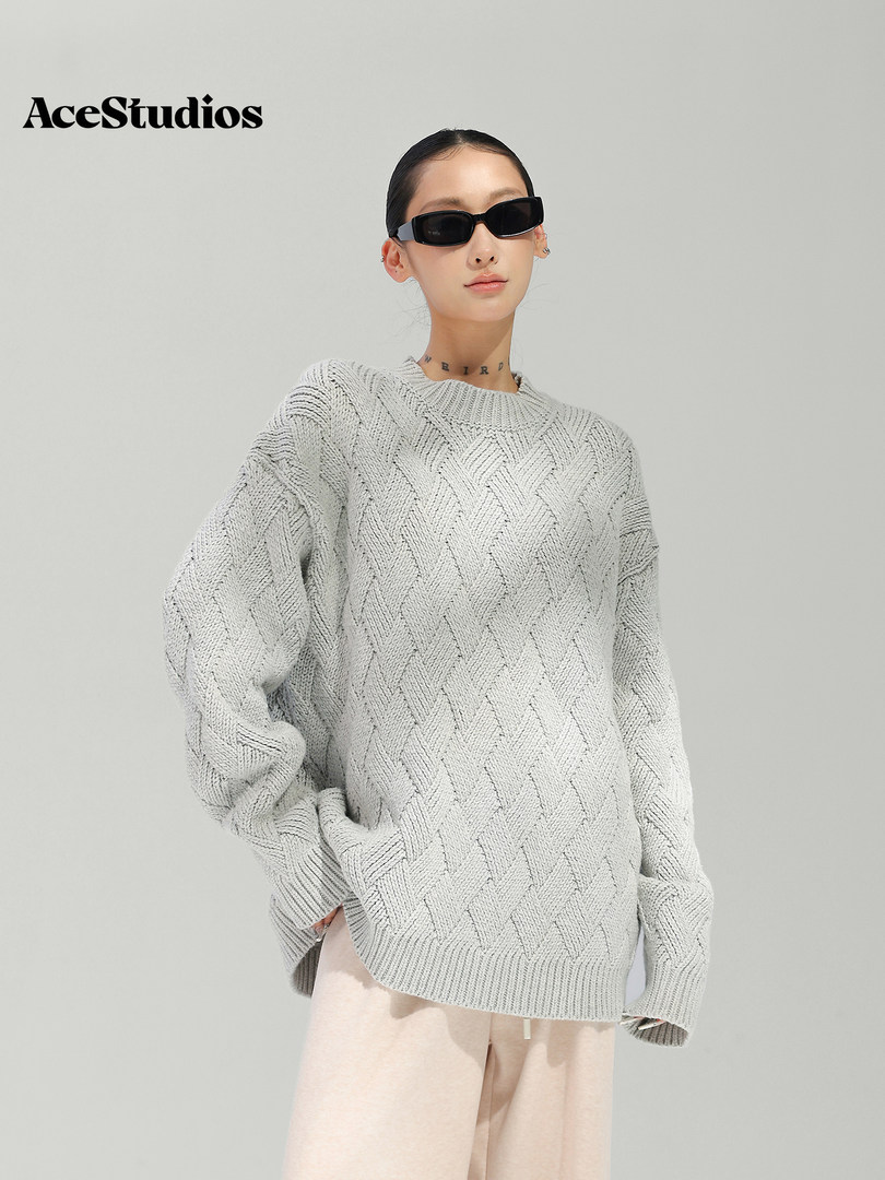 Model wearing a light gray textured knit sweater with beige pants.