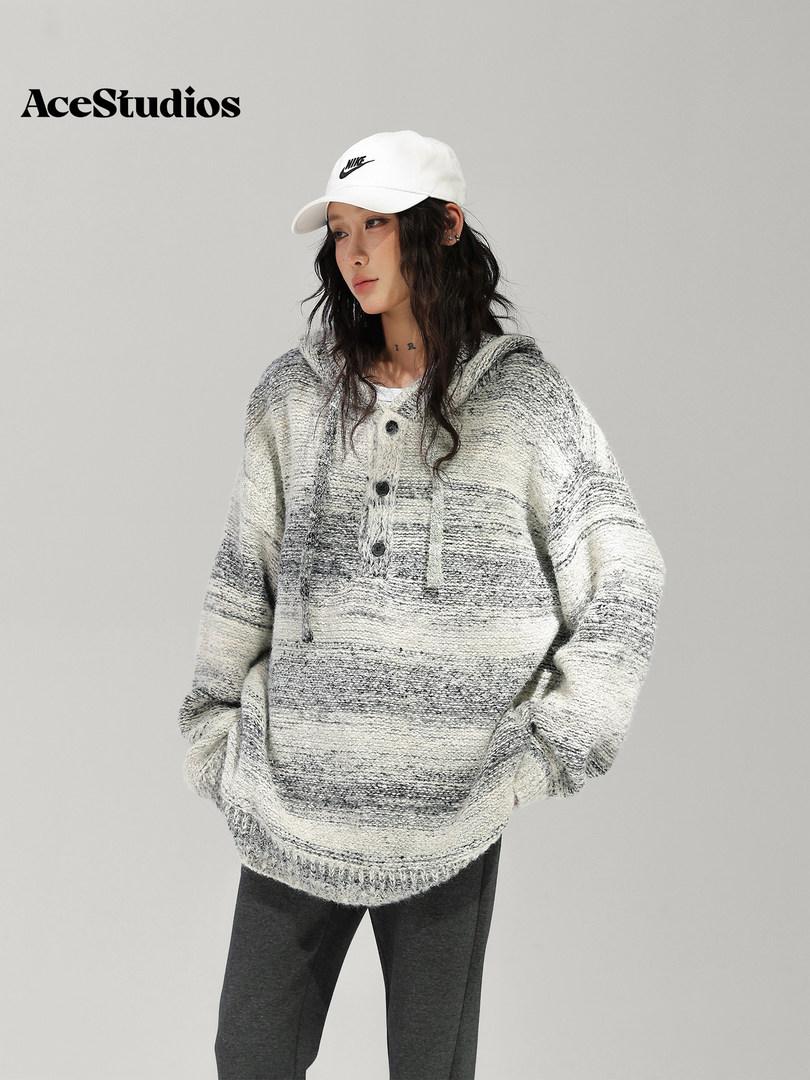 Model wearing a textured oversized gray knit sweater with a white baseball cap