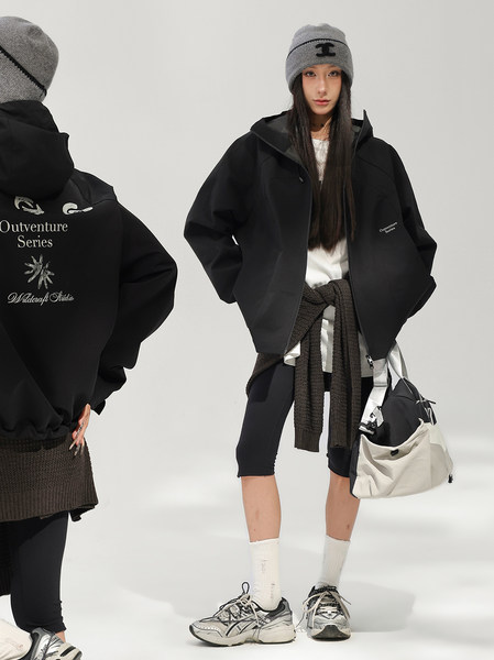 Model wearing a black jacket with beanie, scarf, leggings, sneakers, and a shoulder bag