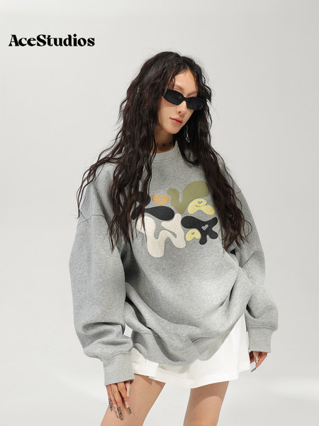 Model wearing an oversized gray graphic sweatshirt with white shorts and black sunglasses