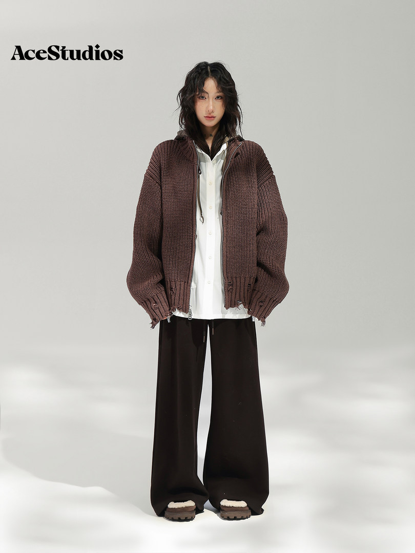 Model wearing a brown textured cardigan over a white shirt with wide-leg black pants.