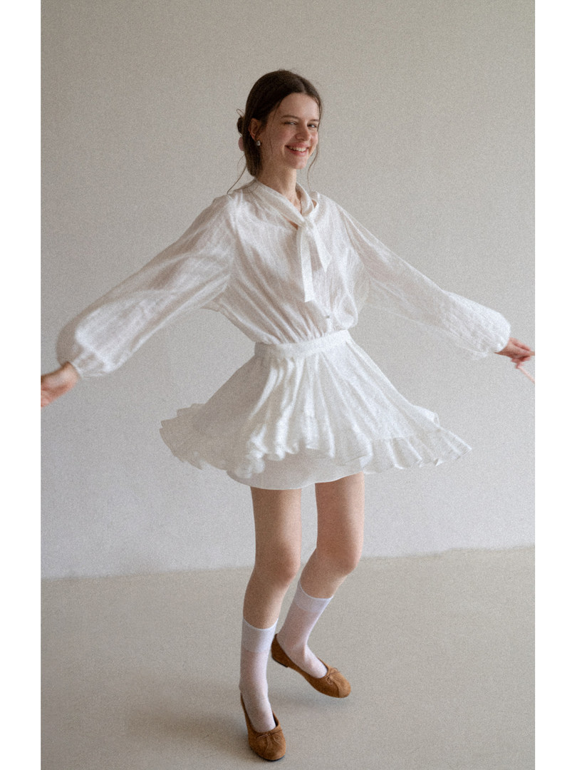 White flowy long-sleeve mini dress worn by a model