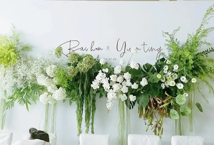 Elegant white and ivory wedding ceremony setup with lush green foliage and white flowers