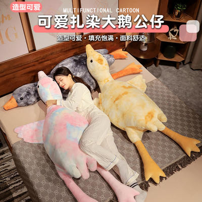 A cute seven-color big goose white doll, plush toy, tie-dyed throw pillow, doll. A girl is sleeping with her legs crossed on the bed