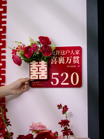 The Newlywed Couple's Bedroom Door Is Decorated with Artificial Flowers to Create a Festive Atmosphere, and the Entrance Door Is Decorated with Wedding Stickers with the Character for Happiness
