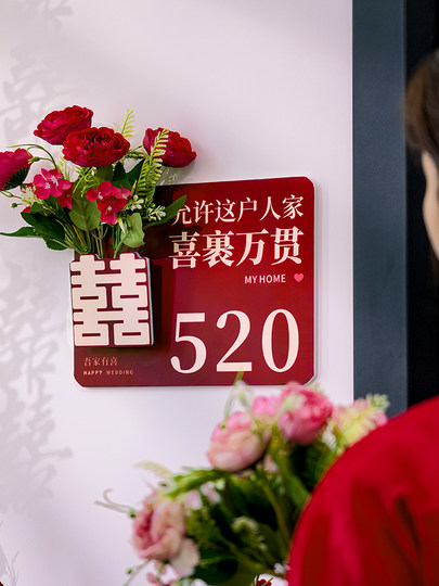 The Newlywed Couple's Bedroom Door Is Decorated with Artificial Flowers to Create a Festive Atmosphere, and the Entrance Door Is Decorated with Wedding Stickers with the Character for Happiness