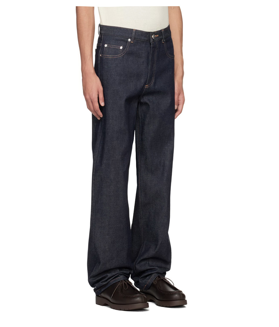 A person stands with arms relaxed at their sides, wearing a white shirt, EastLyst Classic American Straight Leg Jeans in dark blue, and dark brown shoes against a plain white background.