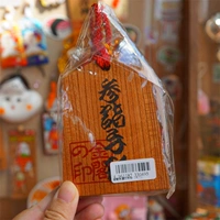 Фигурка автомобиля, висящая на руке в храме Кинкакудзи