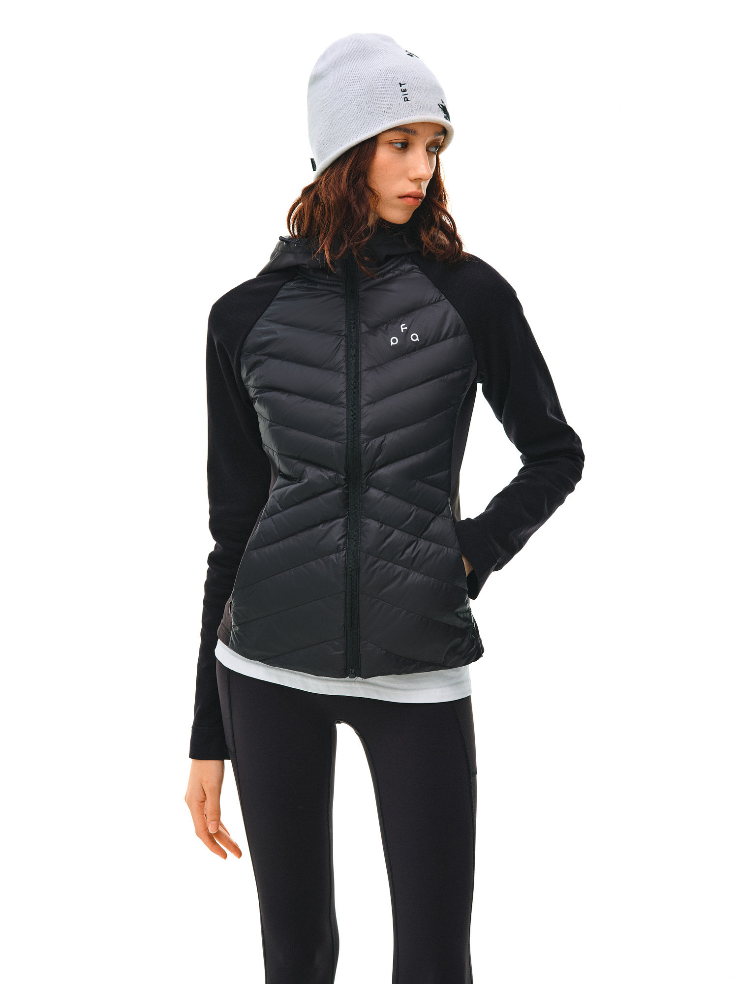 A woman models the EastLyst Quilted Hooded Down Jacket with a gray beanie, white shirt, and black leggings, standing confidently against a plain white background for effortless, lightweight warmth.