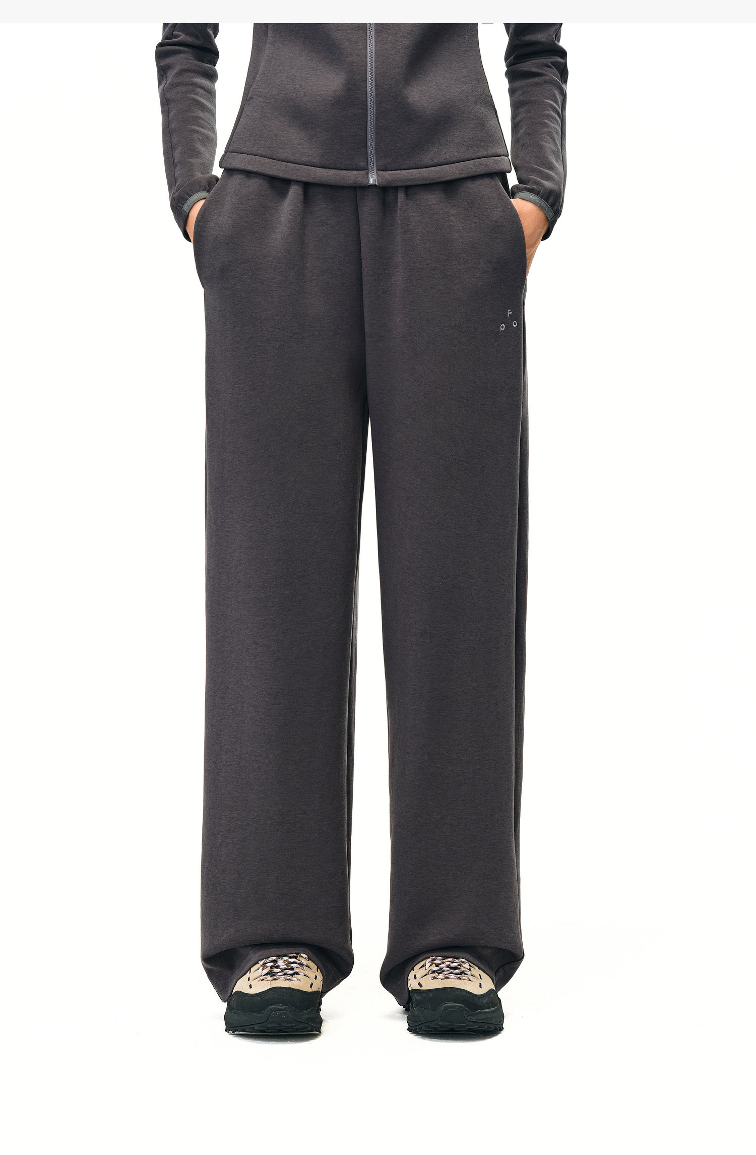 A person wears EastLyst Double-Layer Air-Knit Wide Leg Pants and a matching zip-up top, standing with hands in pockets and beige-black sneakers—the relaxed fit ensures comfort and style for any occasion against a white background.