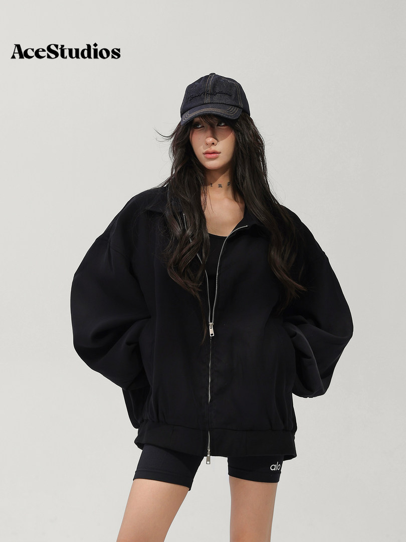 Model wearing a black oversized zip-up jacket with a matching cap and shorts.
