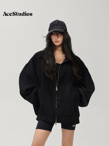 Model wearing a black oversized zip-up jacket with a matching cap and shorts.