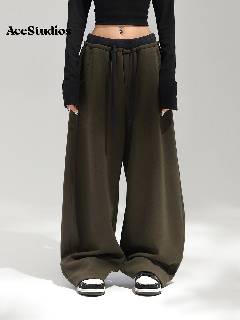 Model wearing oversized dark olive wide-leg pants with a black cropped top and sneakers