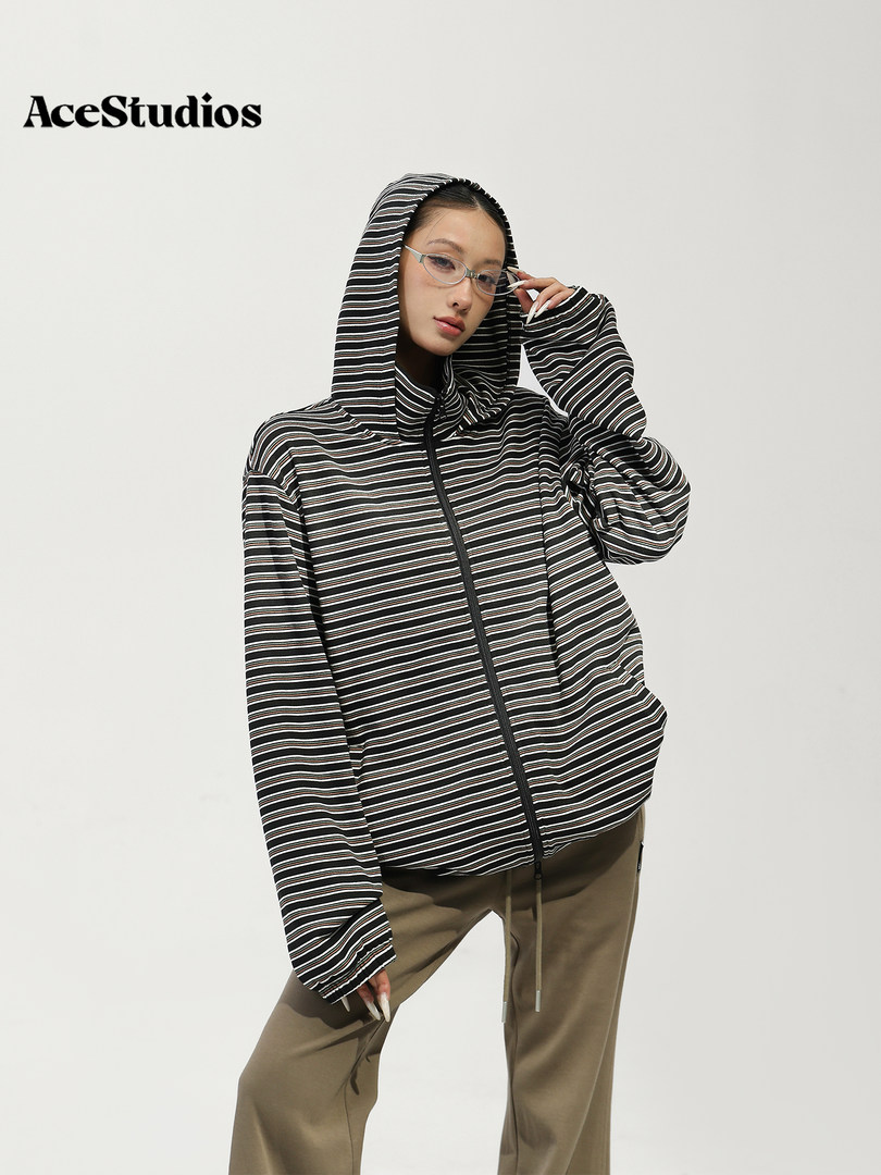 Model wearing a black-and-white striped hooded zip jacket with brown pants