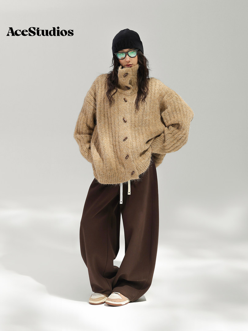 Model wearing an oversized tan knit cardigan with loose brown trousers.