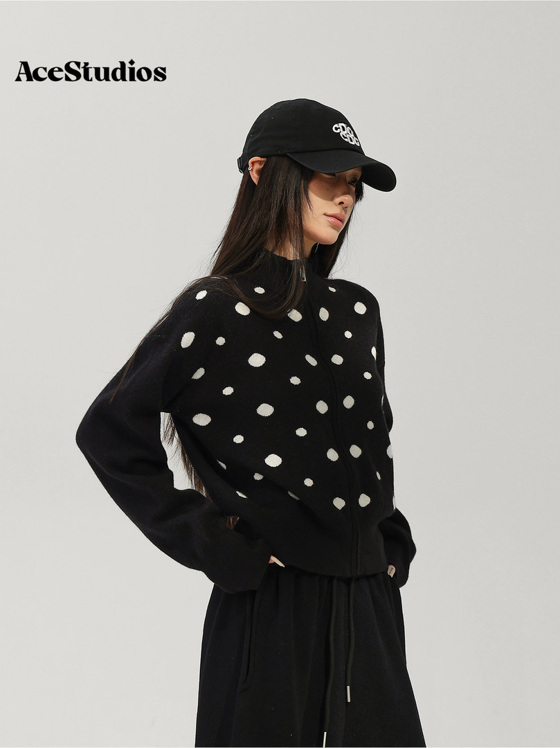 Model wearing a black polka-dot sweater with a black baseball cap and pants