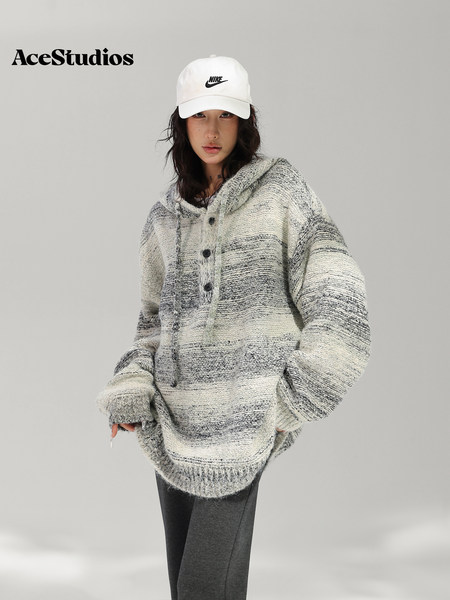 Model wearing an oversized textured gray hooded sweater with a white cap.