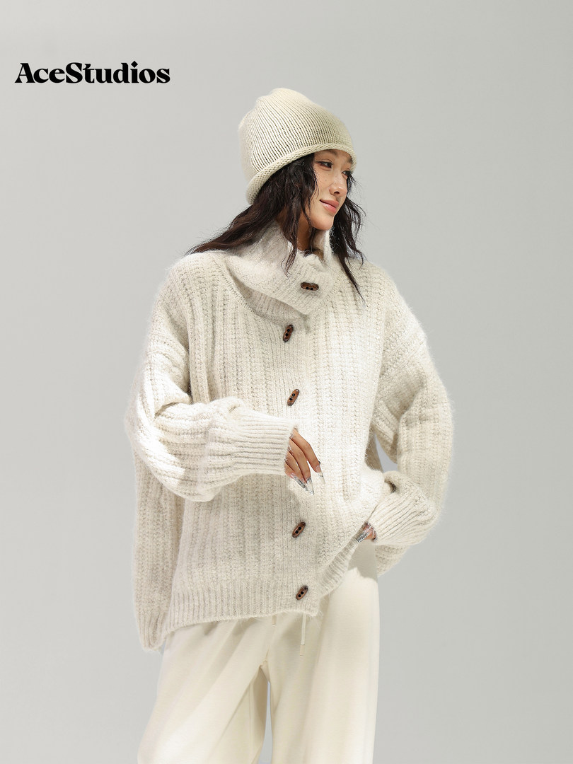 Model wearing a cream chunky-knit sweater and matching beanie.