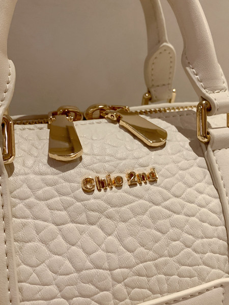 Close-up of a white quilted handbag with gold hardware and brand lettering